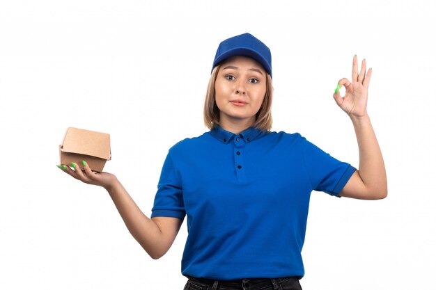 A front view young female courier in blue uniform holding food delivery package