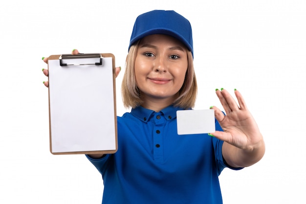 A front view young female courier in blue uniform holding notepad and white card