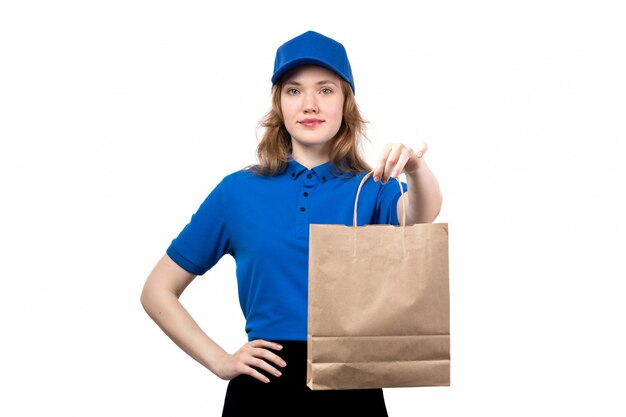 A front view young female courier female worker of food delivery service holding food delivery package smiling on white