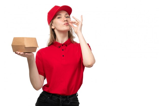 A front view young female courier female worker of food delivery service smiling holding package with food showing tasty sign on white