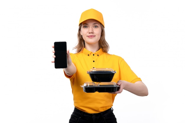 Free photo a front view young female courier female worker of food delivery service smiling holding smartphone and bowls with food on white