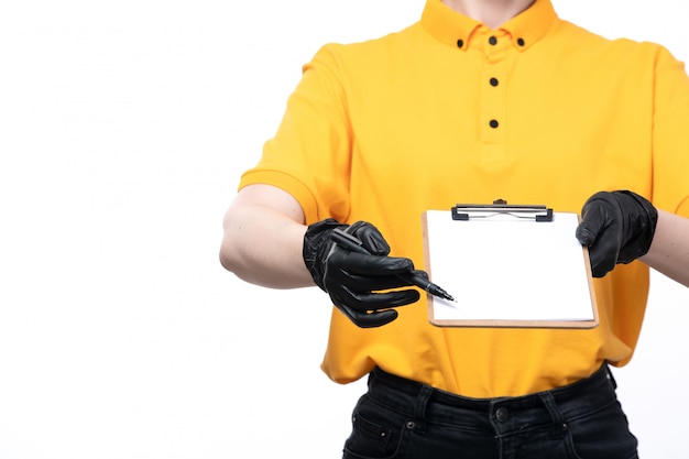 Free Photo a front view young female courier in yellow uniform black gloves and black mask holding notepad asking for the signature