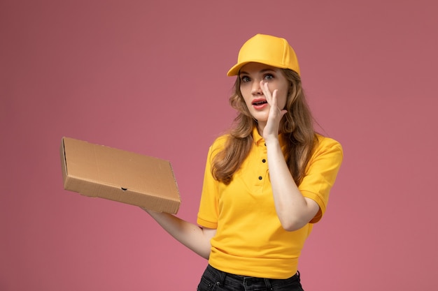 Free Photo front view young female courier in yellow uniform yellow cape holding food delivery box on the dark-pink background uniform delivery service female worker