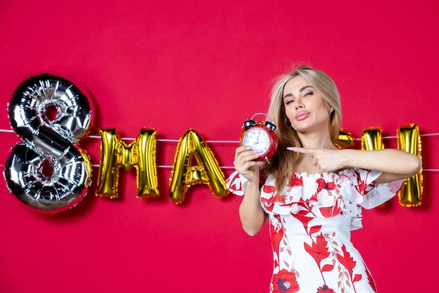 Free photo front view young female in cute dress holding clock on reds time color