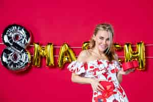 Free photo front view young female in cute dress holding present on decorated red