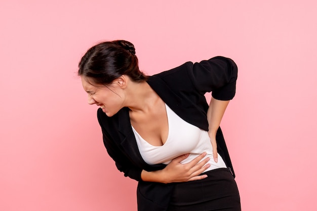 Free photo front view young female in dark jacket suffering from stomachache on a pink background