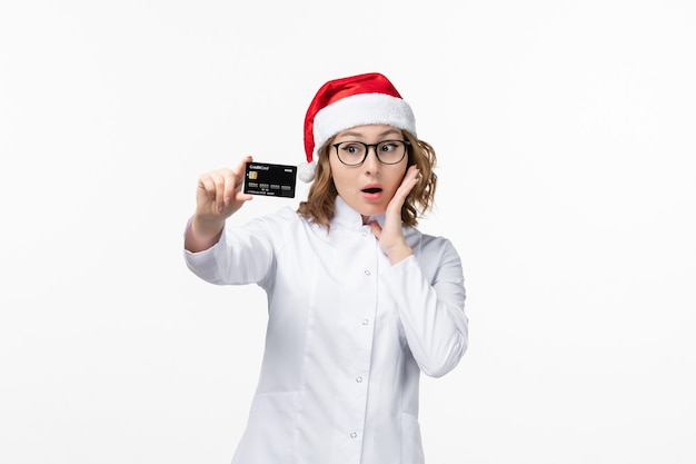 Free photo front view young female doctor holding bank card on white wall holiday nurse new year eve