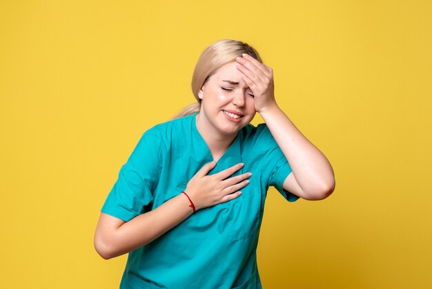 Free photo front view of young female doctor in medical shirt suffering from headache on yellow wall