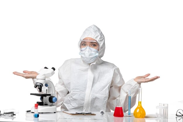 Front view young female doctor in protective suit with mask due to covid sitting posing on white background virus pandemic splash covid-