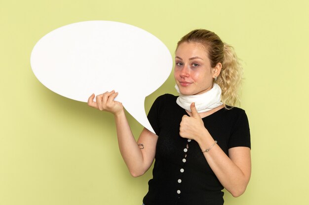 Front view young female feeling very ill and sick holding huge white sign on the green desk sickness medicine health illness