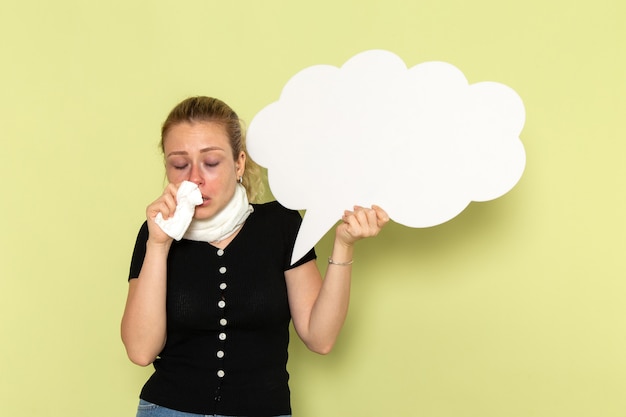 Front view young female feeling very ill and sick holding huge white sign on the green wall girl sickness medicine health illness