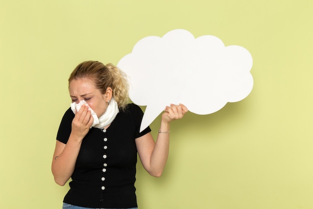 Front view young female feeling very ill and sick holding huge white sign on light-green wall sickness medicine health illness girl