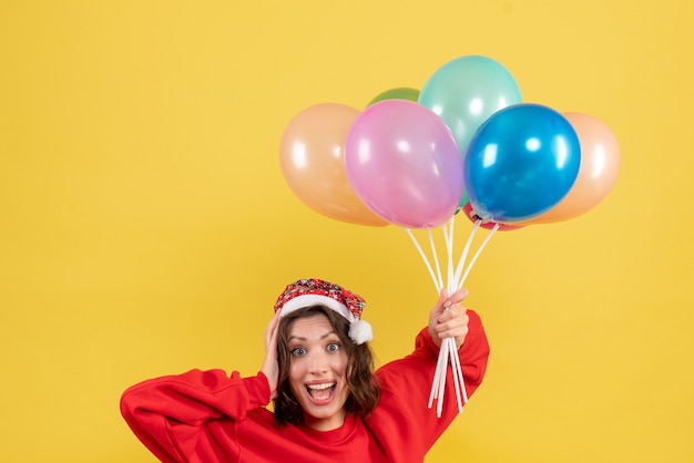 Free photo front view young female holding balloons on yellow