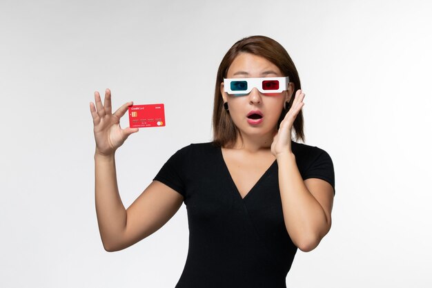 Front view young female holding bank card in -d sunglasses on a white surface