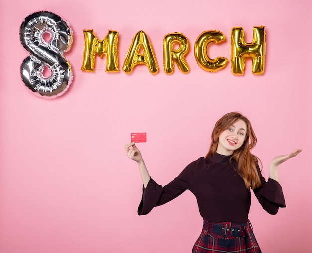 Free photo front view young female holding bank card on pink shopping holidays