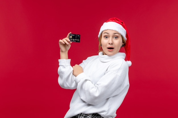 Front view young female holding bank card on red background