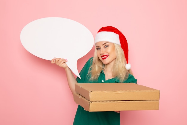 Free Photo front view young female holding big white sign and food boxes on a pink wall photo work new year holiday job courier uniform