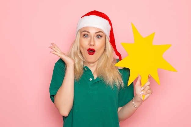 Free photo front view young female holding big yellow figure on pink wall photo work new year holiday job courier