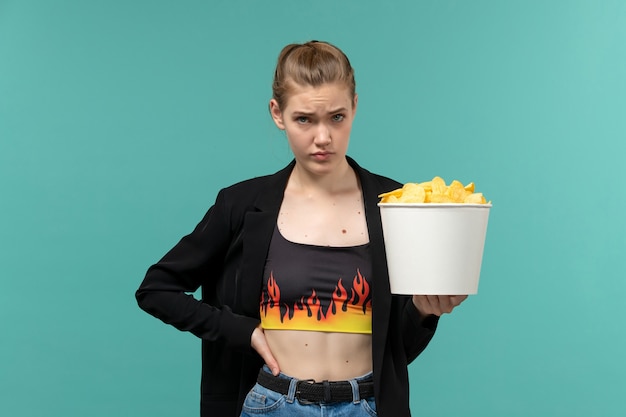 Front view young female holding chips watching movie on blue surface