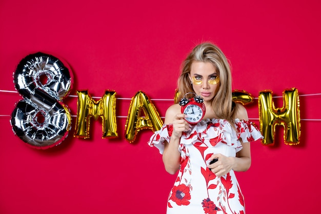 Free photo front view young female holding clocks on decorated red