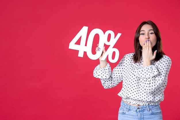 Free Photo front view of young female holding discount on red wall