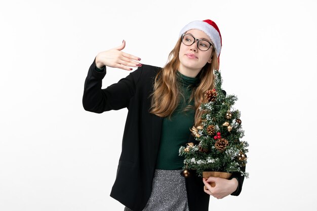 Front view young female holding holiday tree on white desk new year christmas toy