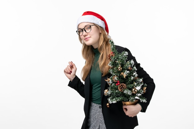 Front view young female holding holiday tree on white desk toy new year christmas