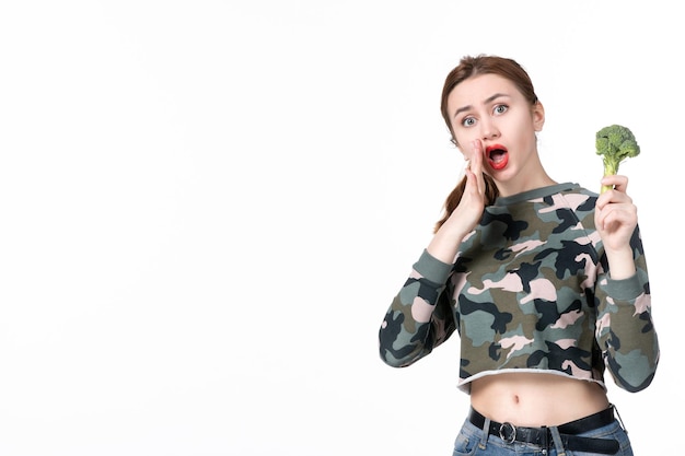 Free photo front view young female holding little green broccoli on white background meal salad dish lunch human healthcare diet food health weight