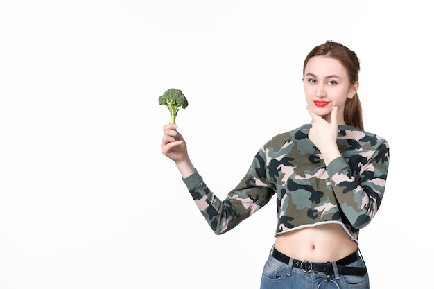 Front view young female holding little green broccoli on white