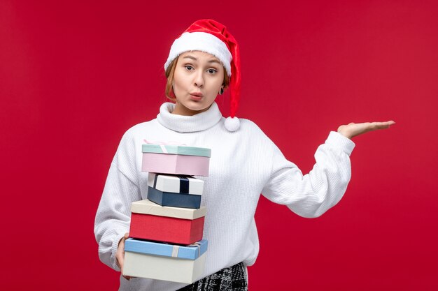 Free photo front view young female holding new year presents on red background