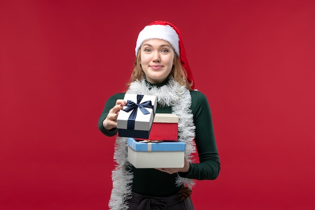 Front view young female holding new year presents on red background