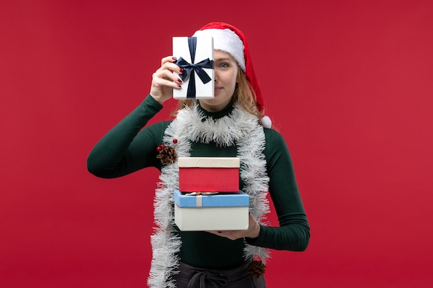 Free Photo front view young female holding new year presents on red background