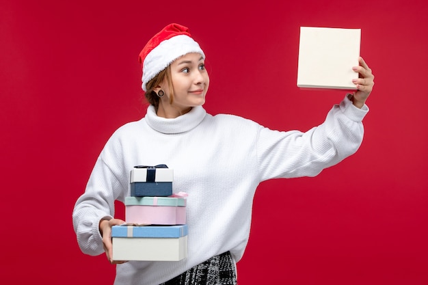 Front view young female holding new year presents on red floor holiday christmas red