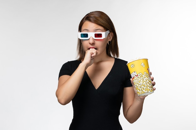 Free Photo front view young female holding popcorn in d sunglasses watching movie on white surface