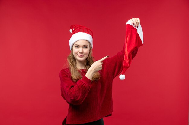 Front view young female holding red cap smiling, christmas holiday christmas