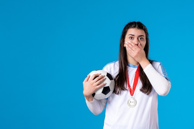 Front view young female holding soccer ball on blue wall