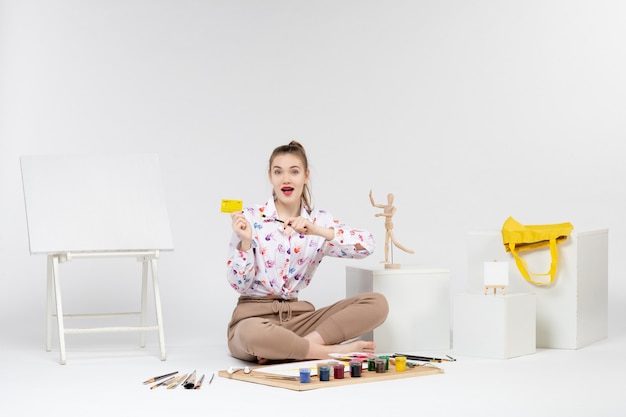 Free photo front view young female holding yellow bank card on white background