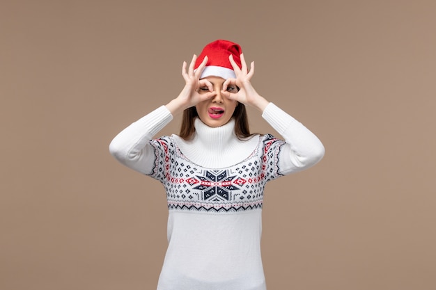 Free Photo front view young female looking through fingers on a brown background emotion christmas holiday