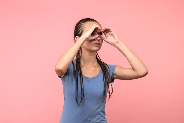 Front view of young female looking through fingers on pink