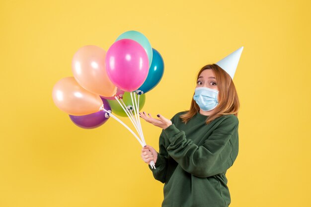 Front view young female in mask holding colorful balloons