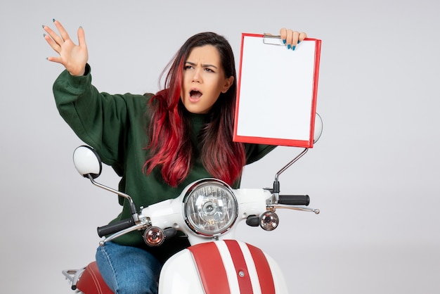 Free photo front view young female on motorcycle holding note for signature on white wall