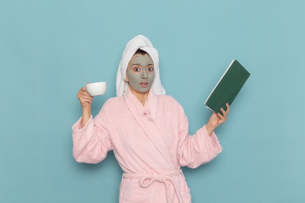 Front view young female in pink bathrobe after shower drinking coffee on the blue wall cleaning beauty clean water selfcare cream shower