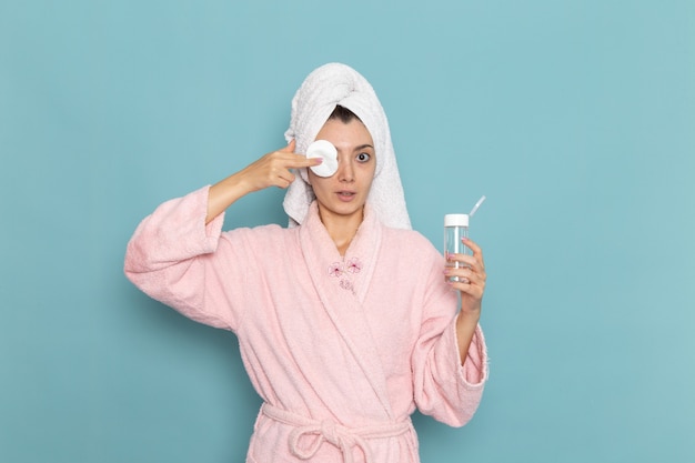 Free Photo front view young female in pink bathrobe cleaning her face from make-up on blue desk cleaning beauty selfcare shower