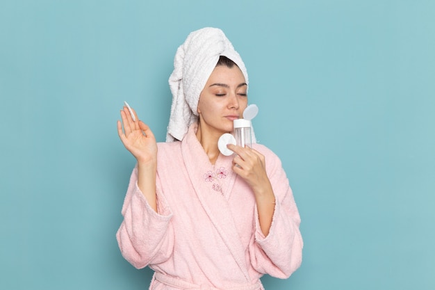 Free Photo front view young female in pink bathrobe holding make-up remover on blue wall cleaning beauty clean water selfcare cream shower