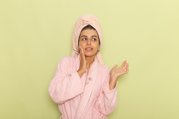 Free Photo front view young female in pink bathrobe posing on a green surface