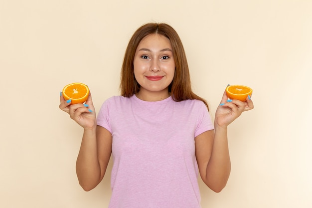 Front view young female in pink t-shirt and blue jeans holding orange with smile