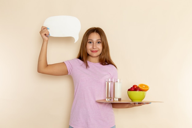 Free photo front view young female in pink t-shirt holding tray fruits milk and water on grey