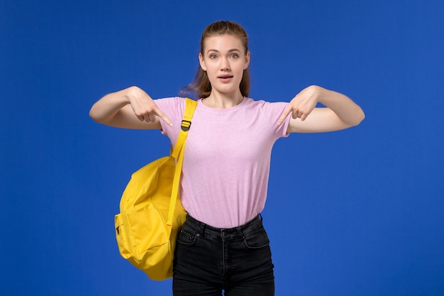 Front view of young female in pink t-shirt wearing yellow backpack posing