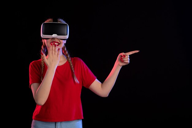 Front view of young female playing vr on dark wall