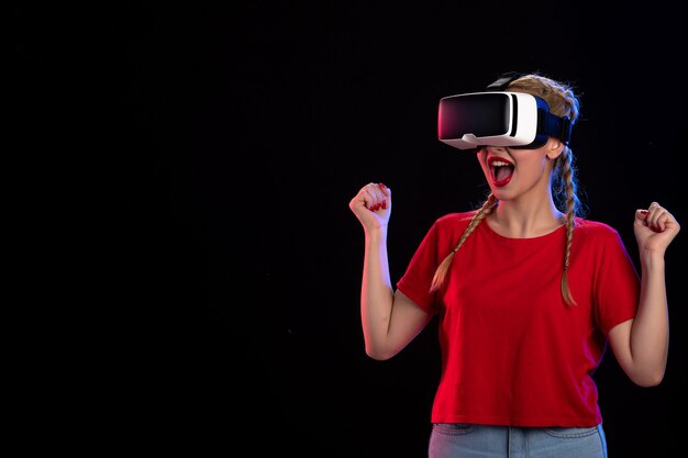 Front view of young female playing vr on dark wall